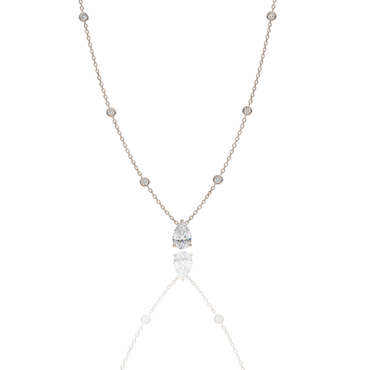 A handcrafted 18kt yellow gold necklace featuring a 1.50 carat G/VS pear-shaped diamond pendant. The delicate gold chain includes 0.40 carats of small, bezel-set diamond accents. Presented by Rebecca’s Diamonds.