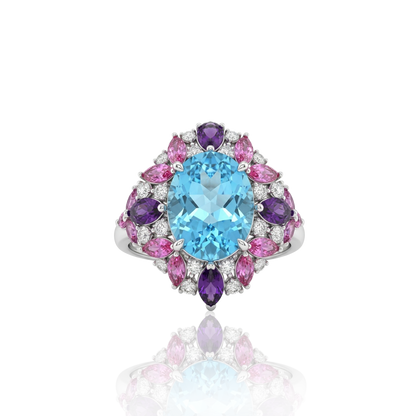 Multi-gemstone cluster statement ring featuring a central light-blue oval gemstone surrounded by pink and purple marquise-cut stones and brilliant accent diamonds, masterfully crafted in 18k white gold by Rebecca’s Heritage.