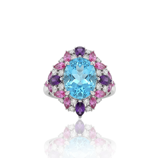 Multi-gemstone cluster statement ring featuring a central light-blue oval gemstone surrounded by pink and purple marquise-cut stones and brilliant accent diamonds, masterfully crafted in 18k white gold by Rebecca’s Heritage.